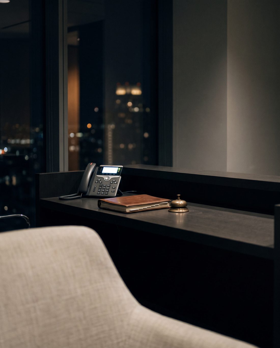 A dark reception desk after closing time, with a single phone lit on the counter.